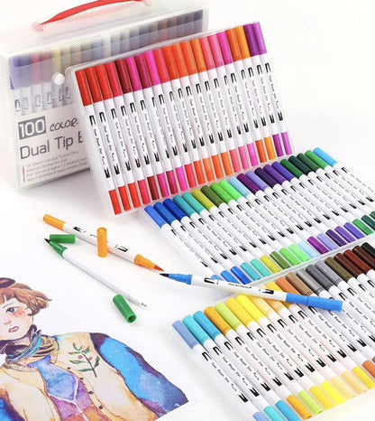 100 colors dual tip brush marker set displayed in plastic case with colorful markers placed on a white surface, accompanied by an illustrated artwork and some marker caps detached.