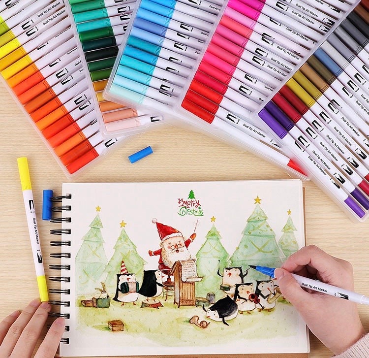 100 Colors Dual Tip Brush Marker Set displayed with vibrant colored pens and an ongoing Christmas-themed drawing.