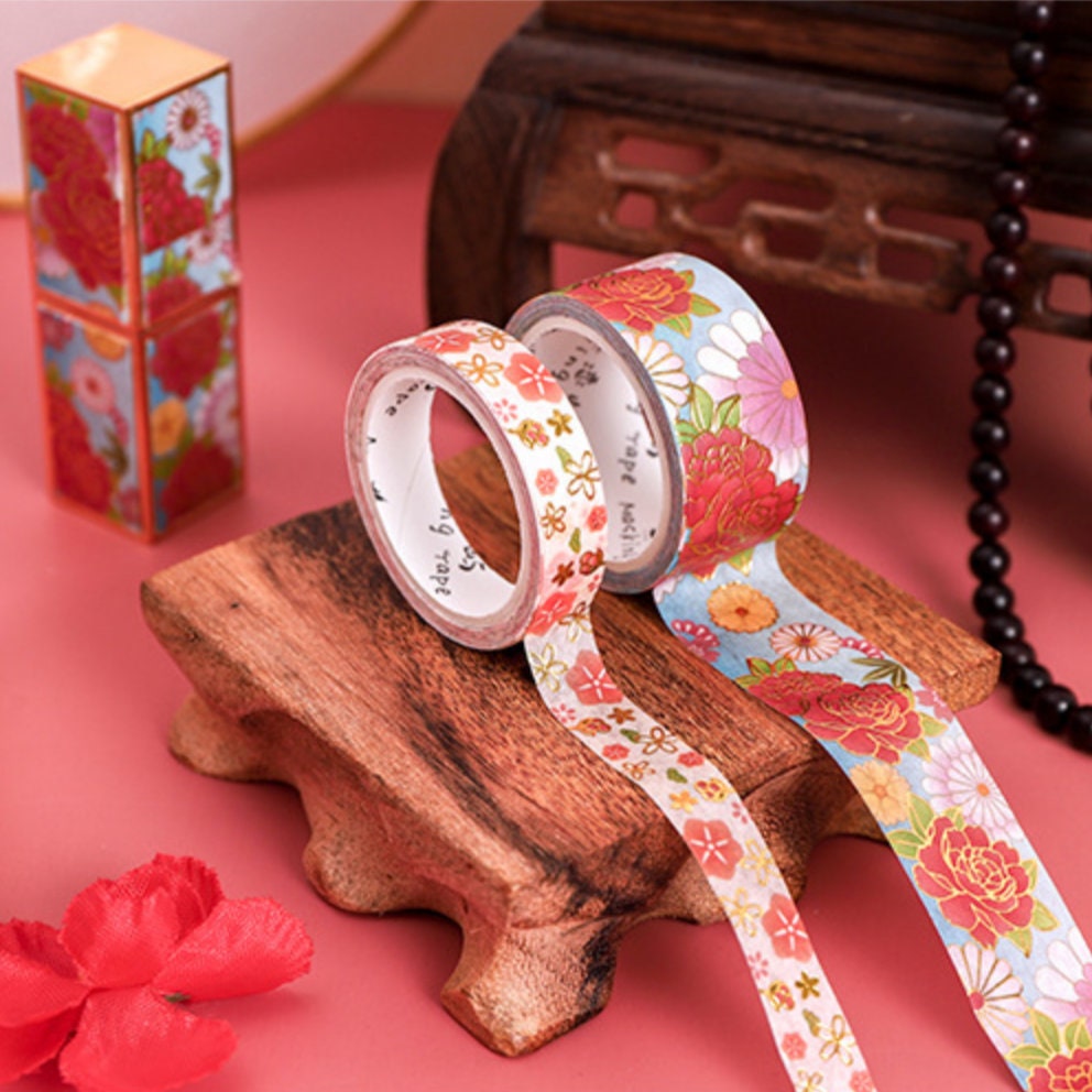 Flower-themed washi tape set with floral designs, perfect for crafts and DIY projects, displayed on a decorative wooden stand.