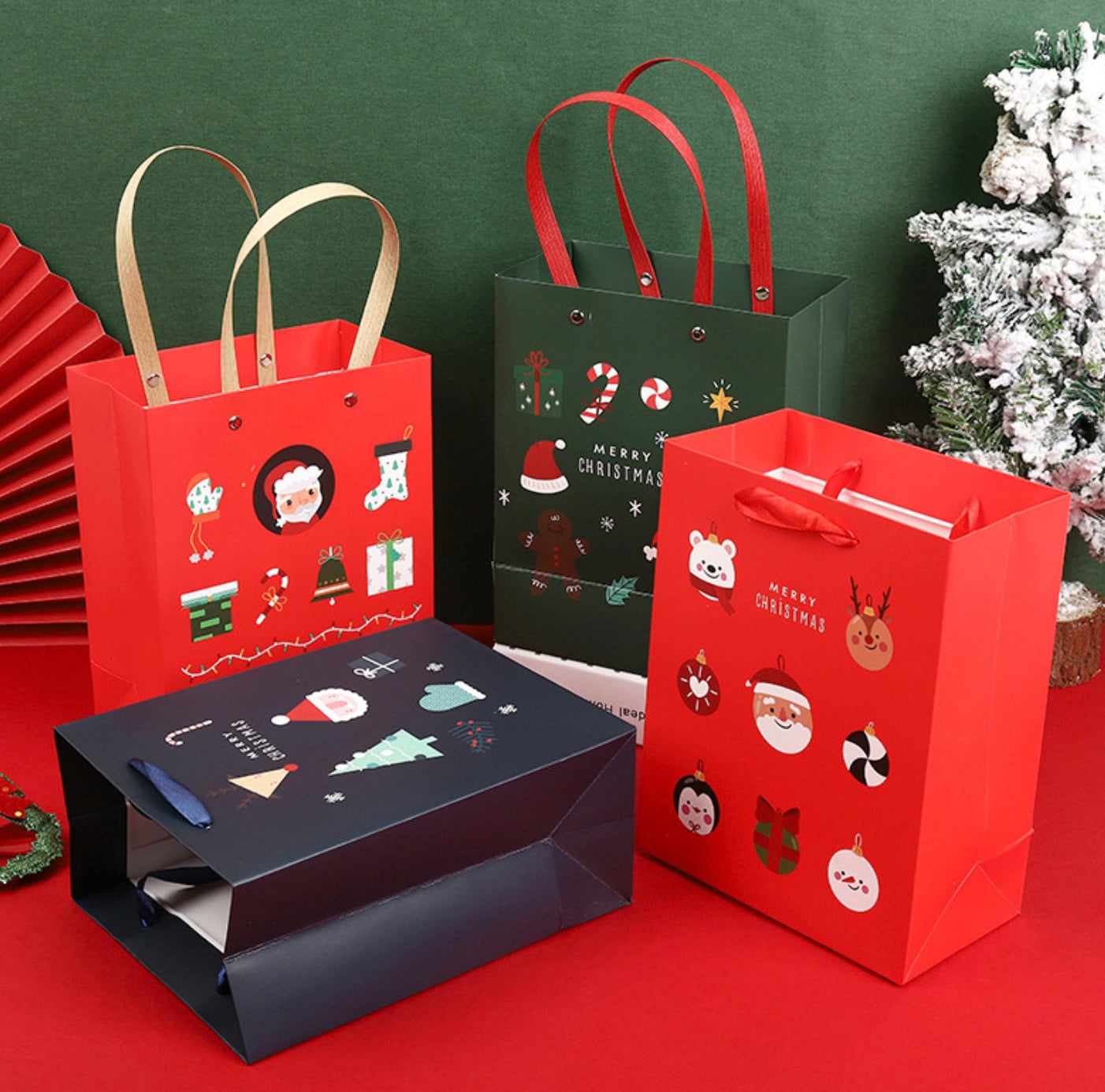 Christmas paper gift bags with handles featuring Santa, reindeer, snowman, and festive designs in red, green, and navy blue colors.