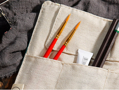 Floral Roll-Up Pencil Case - Artist Brush Holder with beige fabric, holding red paintbrushes, pens, and a small tube.