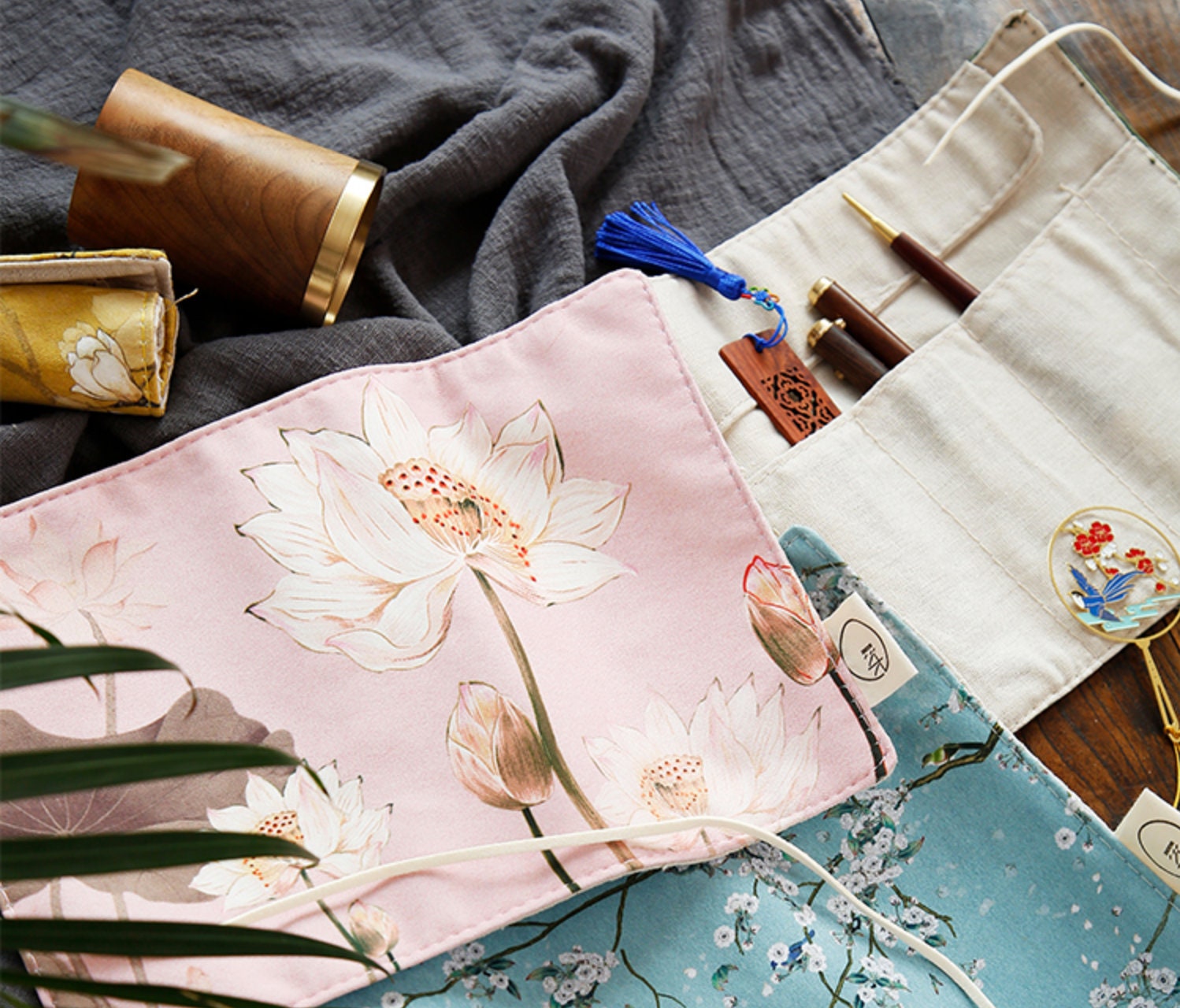 Floral Roll-Up Pencil Case with pink lotus flower design, ideal for artist brushes and stationary storage, displayed on a dark fabric background.