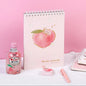 A4 Pink Peach Coil Sketch Book - Cute Planner with kawaii peach design, surrounded by pink-themed stationery and peach drink, on a soft white and pink background