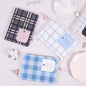 Hard Cover A5 Minimalist Grid Pocket Planner in checkered designs displayed on a pastel background with decorative items.