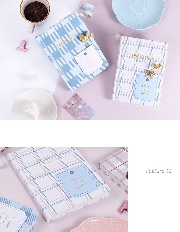 Hard Cover A5 Minimalist Grid Pocket Planner in pastel blue and pink plaid designs with "100 Wishes" and "secret in my pocket" text on the cover, displayed on a pink background with coffee, plates, and stationery items.