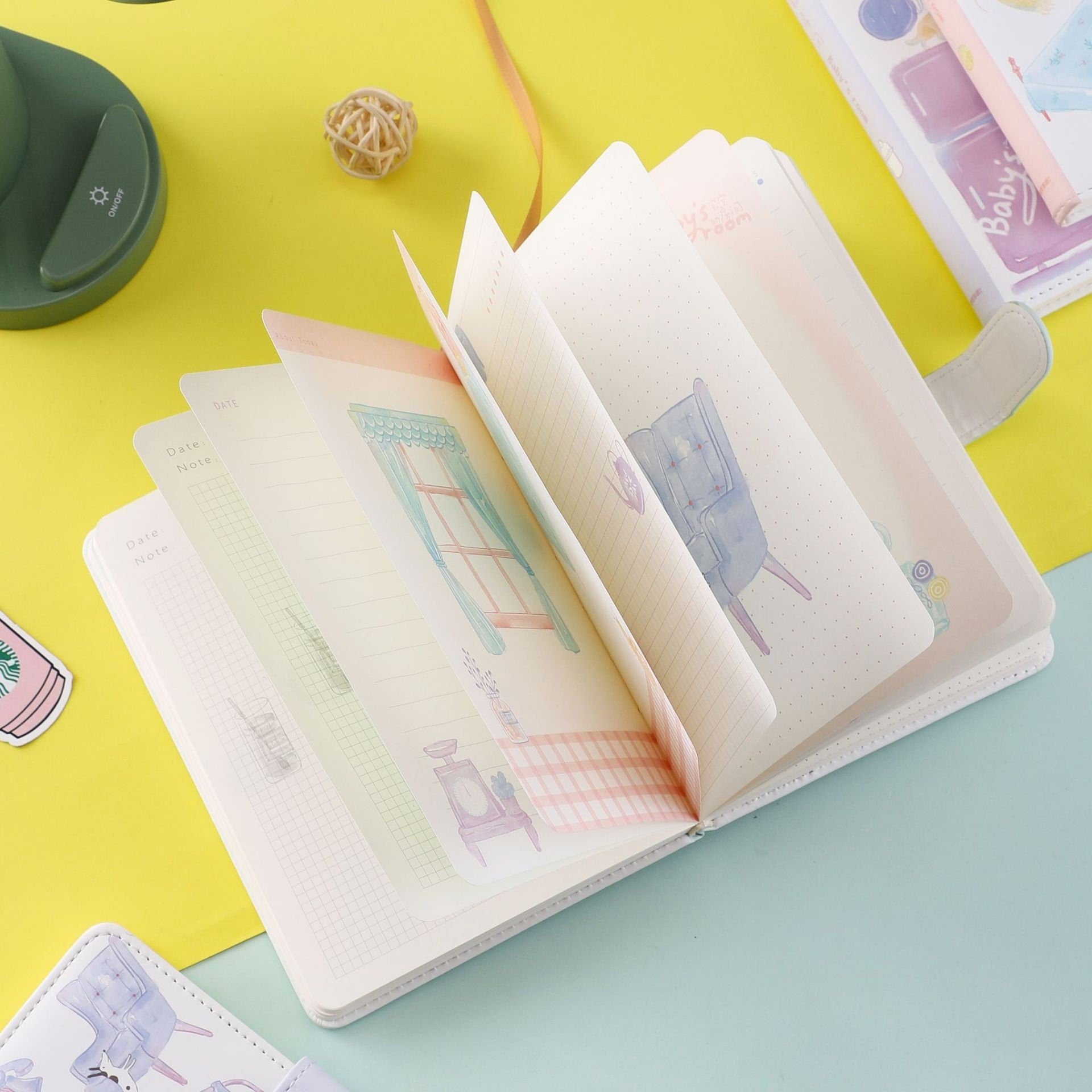 Purple Blue Leather Journal with Magnetic Buckle open showing pastel illustrated pages on a yellow and mint green background.