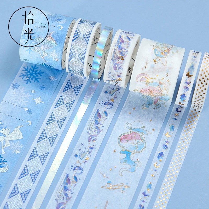 Mercury World Washi Tape Set - 8 Rolls featuring celestial-themed designs, including stars, constellations, snowflakes, and geometric patterns in blue and white colors with gold foil accents.