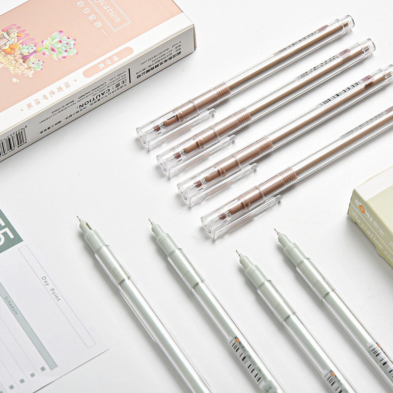 0.5mm minimalist black ink gel pens in clear cases for office use, shown with packaging and notebook on a white surface.