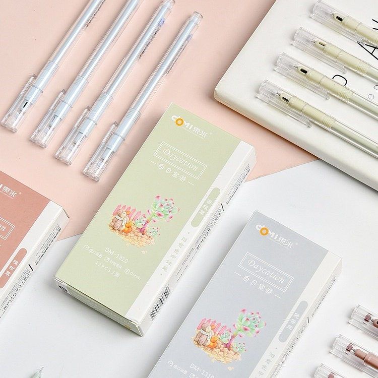 Minimalist 0.5mm black ink gel pens for office use with transparent casing and clear caps, displayed in sets beside pastel-colored packaging boxes featuring cute illustrations.