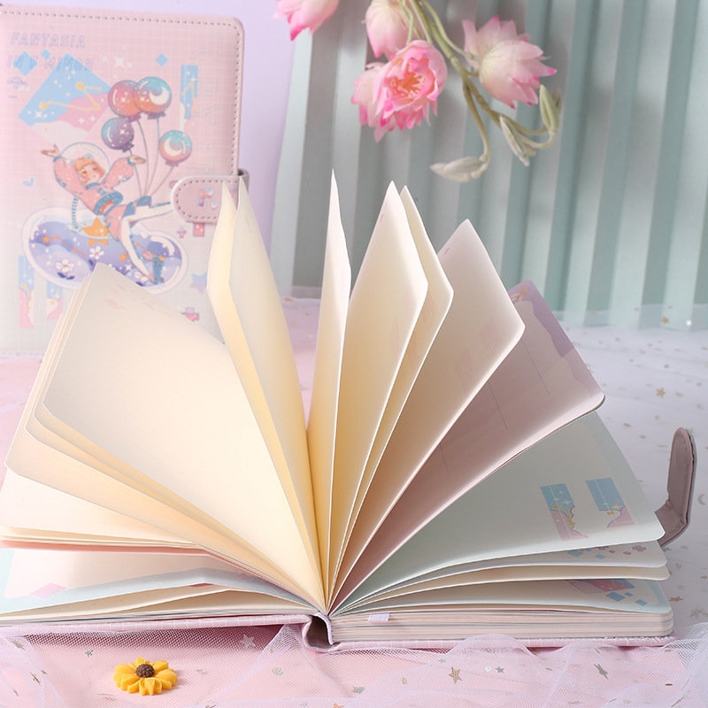 Fantasia in F Minor Journal with leather cover and bookmark, open pages displayed on a pink and white decorative background with flowers.