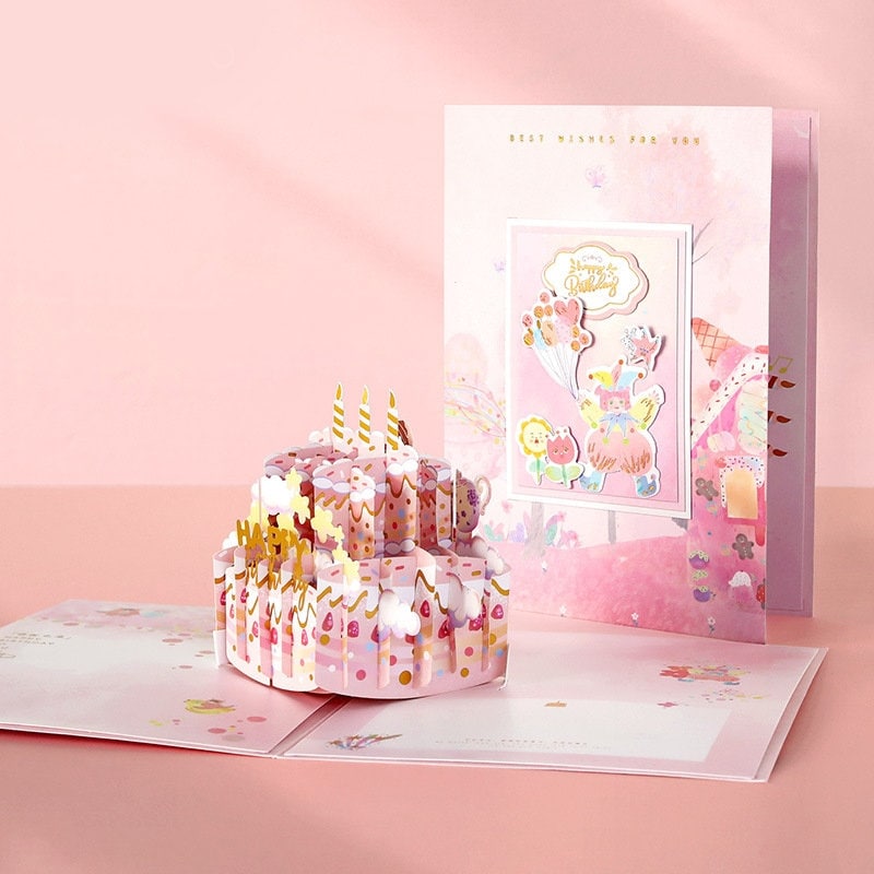 3D Pink Cake Pop Up Card - Happy Birthday with intricate design featuring a pink birthday cake adorned with flowers, candles, and colorful decorations; pastel colors and a cute, kawaii style make it the perfect birthday greeting card.