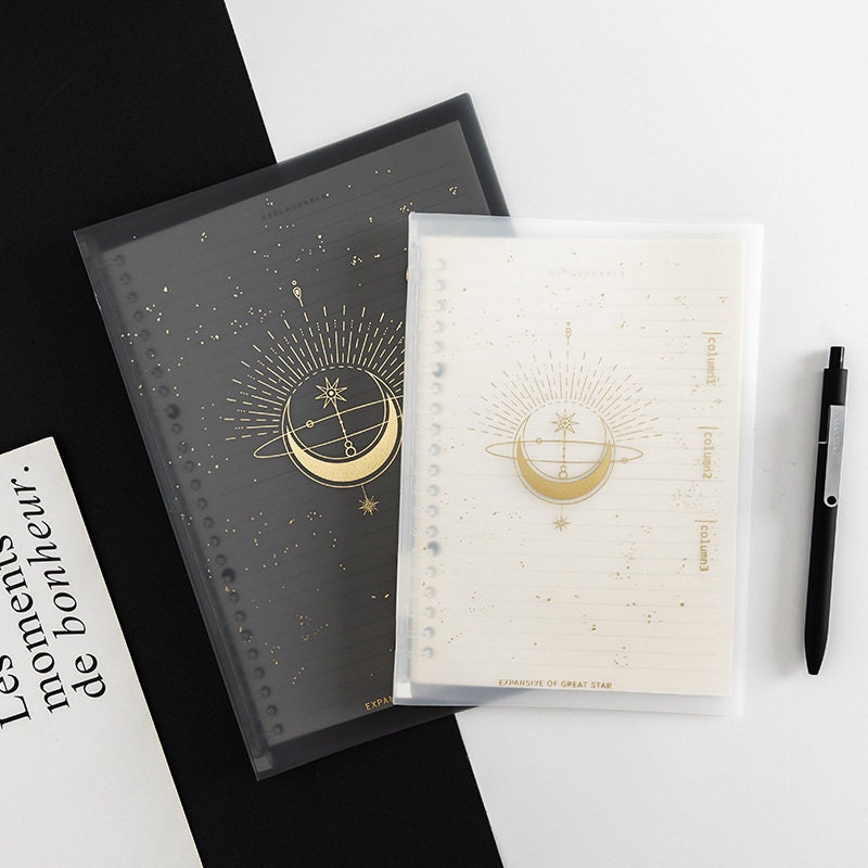 B5 planner with PVC cover featuring golden stars and moons design, available in black and white variants, ideal for note-taking and scheduling.