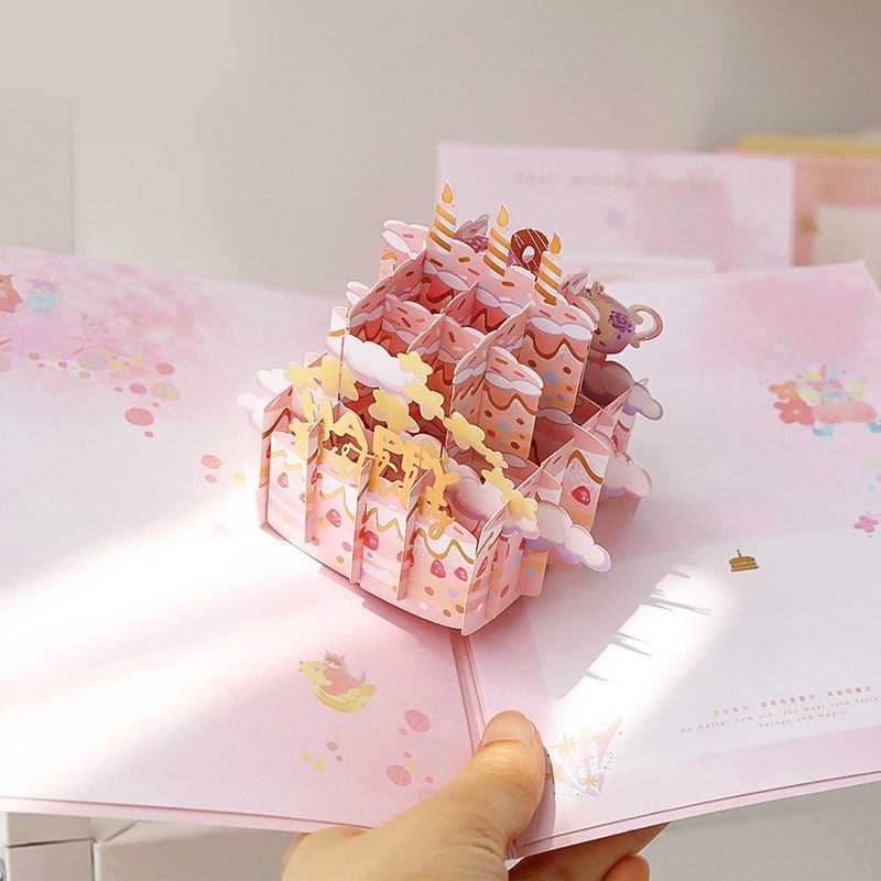 3D Pink Cake Pop Up Card - Happy Birthday featuring an intricate pop-up design of a pink birthday cake with candles and decorations, perfect for kawaii style stationery lovers.