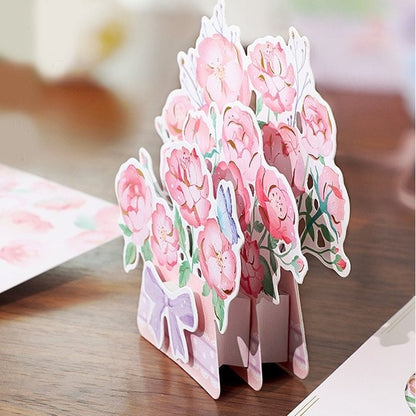 3D Pink Flower Pop-Up Greeting Card featuring delicate Rose and Lily designs with a pastel purple ribbon, perfect for birthdays, anniversaries, or special occasions.