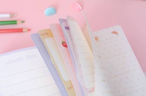 A5 Leather Journal with Animal Design and Bookmark, kawaii style, open pages showing colorful and cute date pages, pink background.