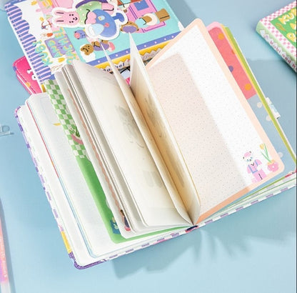 Kubi and Rache Leather Notebook - A5 Magnetic Buckle, open to show colorful and cute Kawaii-style interior pages including grid and dotted pages on a blue background.