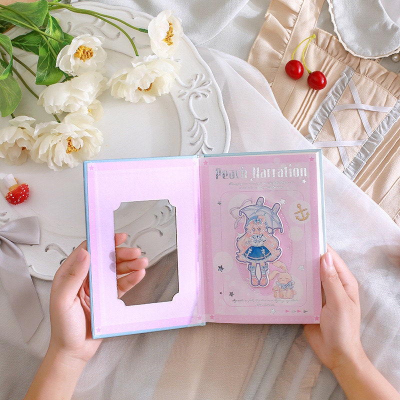 Peach Narration Magnetic Buckle Journal with Bookmark featuring adorable kawaii character design, pink pages, and decorative detailing, held by hands with white flowers and cherries in the background.