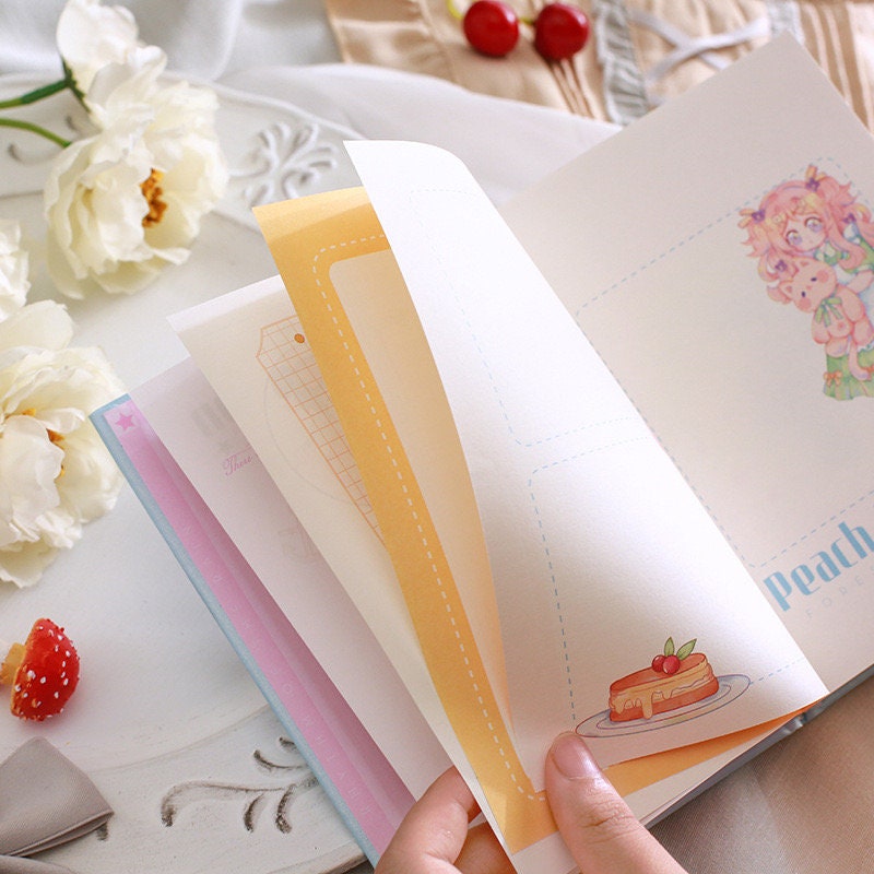 Peach Narration Magnetic Buckle Journal with Bookmark being flipped open, showing colorful kawaii-style illustrations and decorative pages; cute stationary with cake and character drawings.