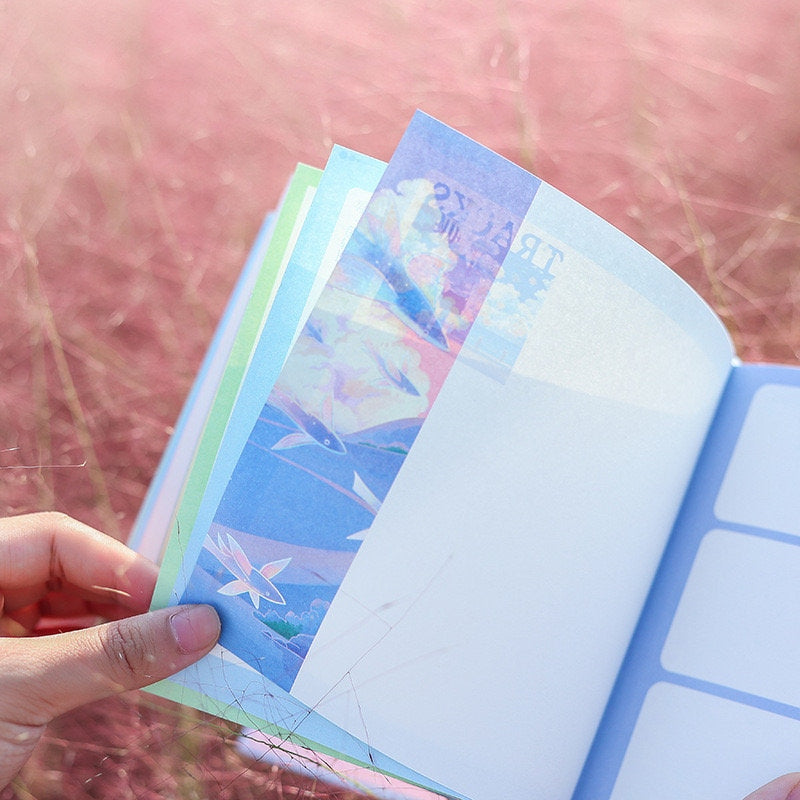 Fish Hear Sea hard cover journal with bookmark, showing colorful ocean-themed illustrations inside against a blurry pink background.