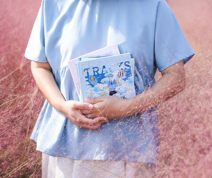 Person holding Fish Hear Sea Hard Cover Journal with Bookmark in a field of pink grass