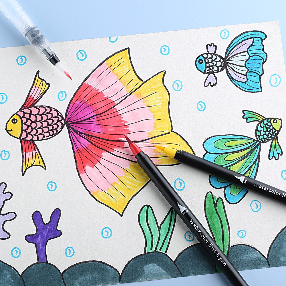 Colorful drawing of fish using 48 vibrant watercolor brush pens with precision soft tips, including red and yellow pens shown on paper, ideal for artists and hobbyists.