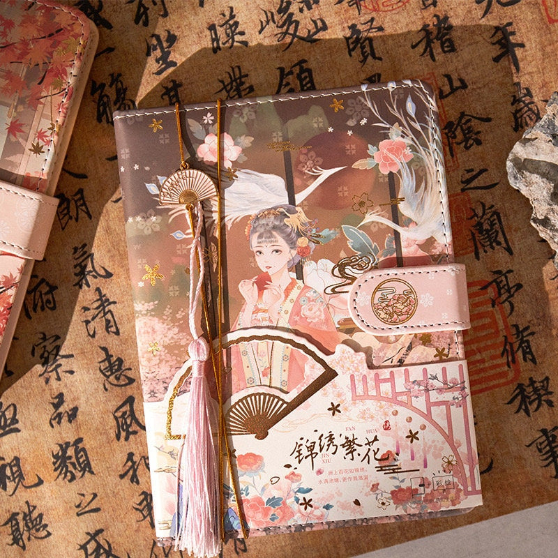 Asian Beauty Leather Planner with Metal Bookmark featuring traditional artwork of an elegant woman in kimono, adorned with floral and fan designs, pink tassel, and secure clasp.