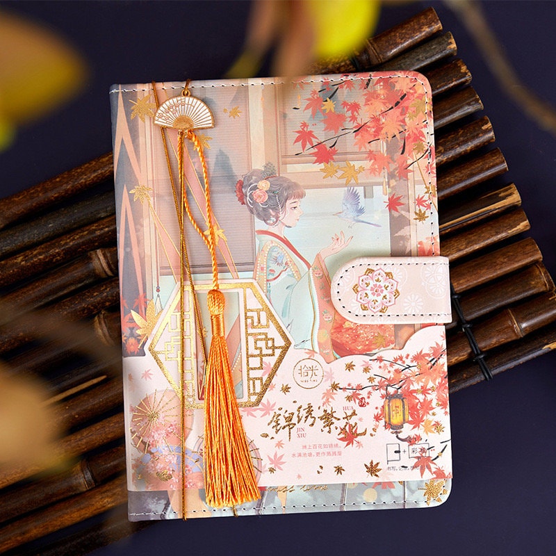 Asian Beauty Leather Planner with Metal Bookmark featuring an elegant Asian-inspired design, intricate illustrations, and a decorative yellow tassel bookmark. Perfect for organizing and adding a touch of elegance to your daily routine.