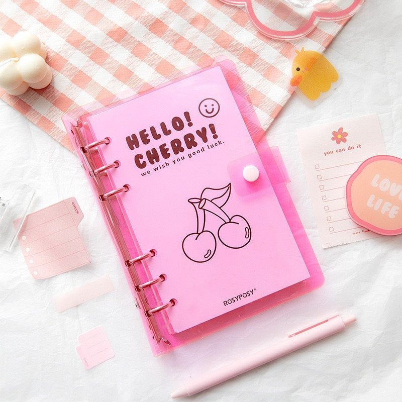 A6 Loose Leaf Planner with Stickers and Cards in pink with cherry design on cover, surrounded by cute stationery items like a pink pen, love life sticky notes, and encouraging cards.