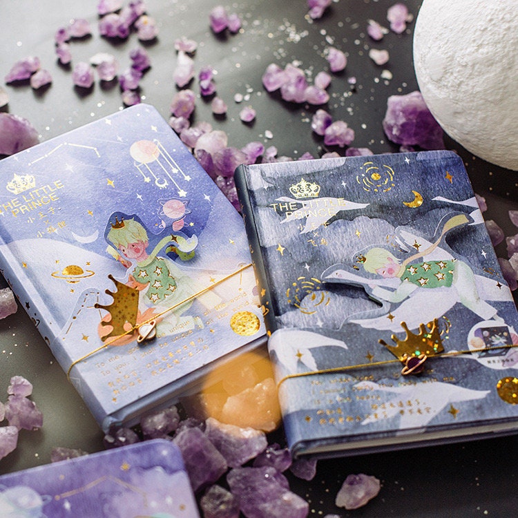 The Little Prince A5 3D Notebook with Bookmark featuring a whimsical cover design, surrounded by amethyst crystals and moon-themed decor, perfect for journaling or taking notes.