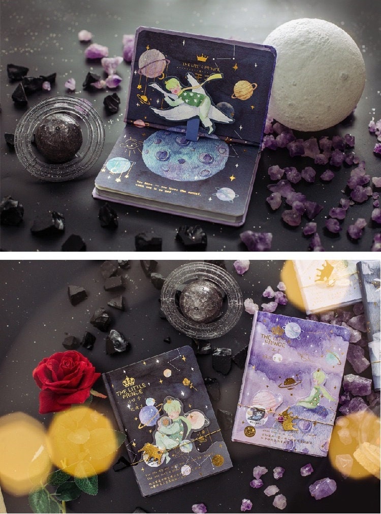 The Little Prince A5 3D Notebook with Bookmark on a starry black background, surrounded by purple and black crystals and a red rose, showcasing whimsical 3D illustrations of The Little Prince in space.