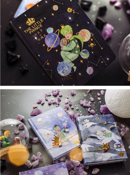 The Little Prince A5 3D Notebook with Bookmark featuring an illustration of The Little Prince among stars and planets, surrounded by purple and black crystals on a decorative background.