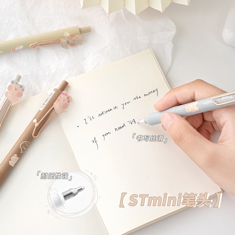 Kawaii Animal Gel Pens 0.5mm Black Ink - 6 Pack being used to write in a notebook, featuring a cute animal design on pen clips and smooth writing performance.