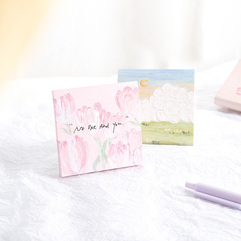 Flower Field Sticky Notes Set with 120 Pieces, featuring two sticky note designs with pastel-colored flower and field illustrations, laid out on a white surface with a purple pen.