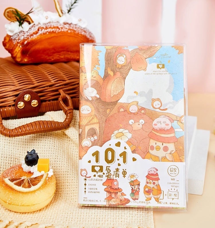 Crystal Cover Rainbow Town Journal with 192 A5 Pages featuring cute pastel illustrations of animals and trees, set on a wooden basket backdrop with pastries.