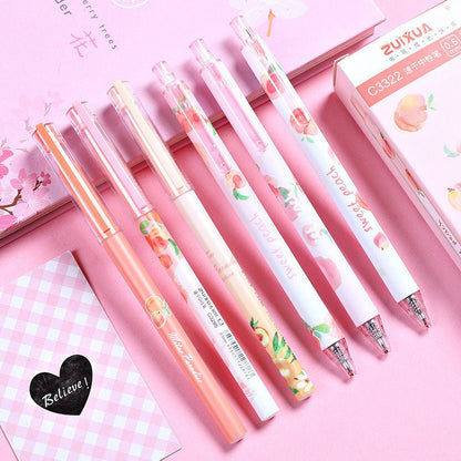 Peach Scented 0.5mm Kawaii Gel Pens in pastel pink packaging with peach-themed designs, displayed on a pink background with cherry blossom and checkered pattern notebooks