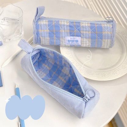 Double-sided milky cream fabric pencil case in kawaii style with blue plaid design and quilted texture, featuring zip closure and a decorative loop, perfect for storing pens and stationery.