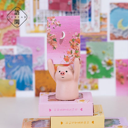 Rainbow Dream Decorative Scrapbook Paper - 60 Pages displayed with a cute pig figurine holding a pink floral scrapbook paper, surrounded by colorful and kawaii-style backgrounds.