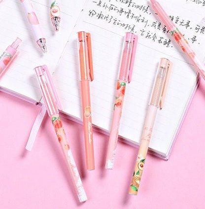 Peach Scented 0.5mm Kawaii Gel Pen with adorable peach-themed designs displayed on an open notebook with pink background.