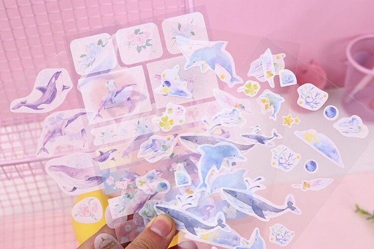 Kawaii Dolphin Ocean Stickers Set - 20 Designs featuring cute dolphin illustrations, floral patterns, and ocean-themed elements on transparent sticker sheets. Cute stationary supplies for planners, scrapbooking, and crafting.