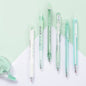 Kawaii black ink gel pens set 0.5mm, featuring six assorted pens in pastel shades of green and white, arranged on a light green and white background.