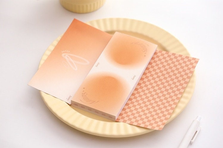 Dreamy Island Notepad Set - 90 Sticky Notes in pastel peach and orange tones, displayed on a yellow plate with a white pen nearby