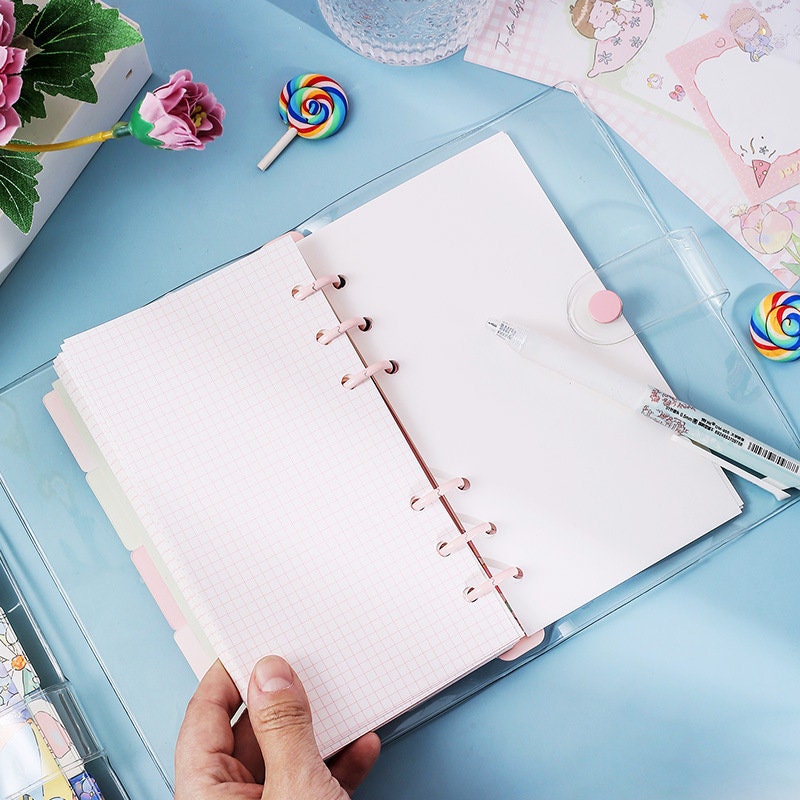 Dorothy A6 Loose Leaf Notebook with pink grid paper, translucent cover, and included ruler, kawaii stationery on blue background with colorful lollipops and flowers.