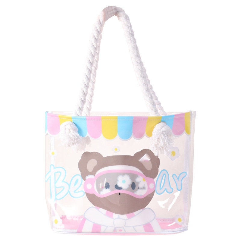 Clear vinyl tote bag with cute bear animal design, pastel colors, white rope handles, kawaii style handbag.