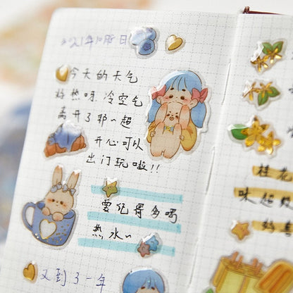 Kawaii gold foil jelly stickers in use on a notebook page with cute characters, stars, and floral designs. Perfect for craft and DIY projects.