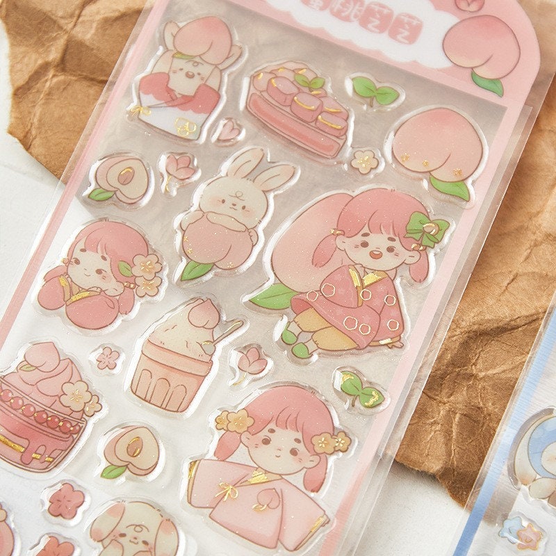 Kawaii Gold Foil Jelly Stickers featuring adorable pink-themed characters, including cute girls in kimono, a bunny with a peach, and various sweet treats, perfect for craft and DIY projects.