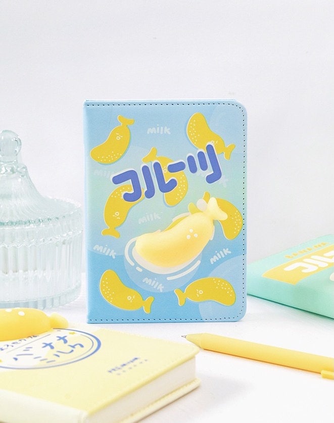 Banana soft leather journal DIY planner in kawaii style with cute banana design, light blue cover, surrounded by pastel-colored stationery.