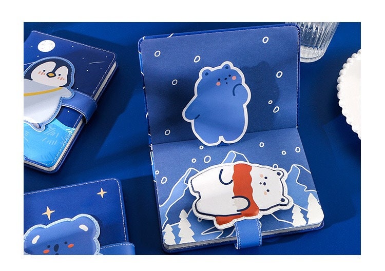 Blue Leather Animal Journal with Magnetic Buckle featuring cute bear and penguin designs on blue backgrounds with snowy and night sky themes.