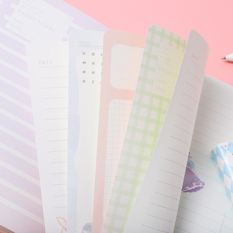 Alice Dream Journal pages with gold foil leather cover, featuring pastel colors, date sections, and grid designs on a pink background.