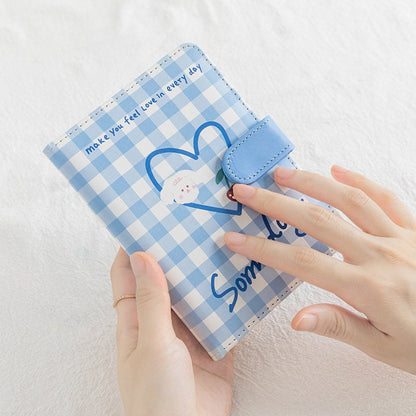 Blue A6 notebook with magnetic buckle, featuring a kawaii style leather grid planner design with heart and cute character illustration.