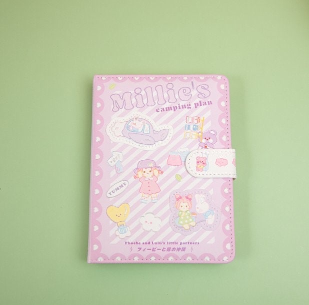 Millie's Leather Camping Journal with colorful pages, pastel pink cover featuring cute kawaii camping illustrations, secure clasp, perfect for kids and journaling enthusiasts.